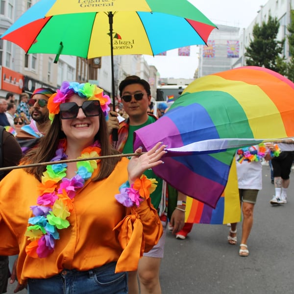 An L&G employee marching in a pride parade, waving a rainbow flag.