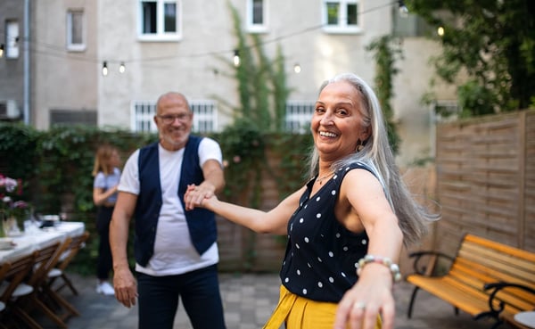 Senior Woman Dancing With Husband Outdoors In Garden