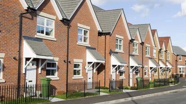 A row of terraced houses, with pristine green front gardens.