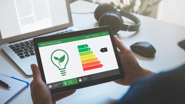 Photograph of a person's hands holding an iPad with energy rating on the screen