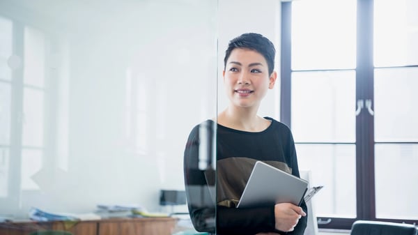 Photograph of a woman in an office holding an iPad