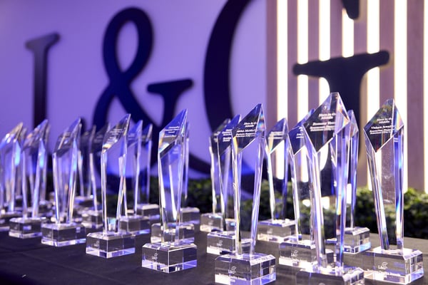 Rows of crystal trophies displayed on a table at L&G's 15th annual Business Quality Awards, with the L&G logo visible in the background.