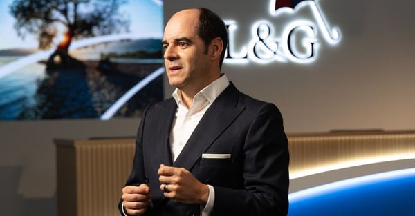 Behind‑the‑scenes style image showing Group CEO, António Simões, standing in a darkened events space with the L&G logo projected on the wall behind him.