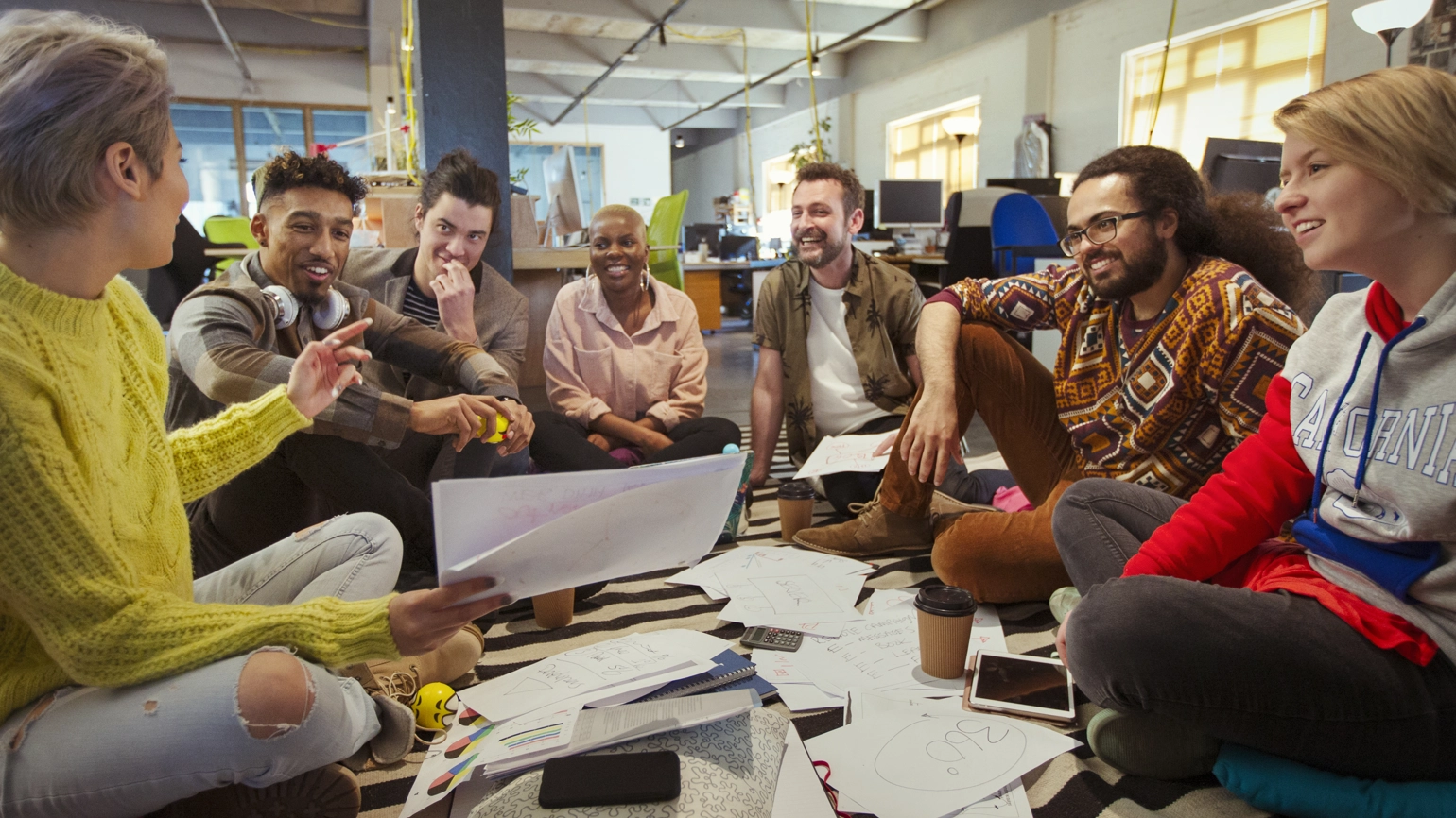Group of individuals sitting on the floor in discussion Group of individuals sitting on the floor in discussion