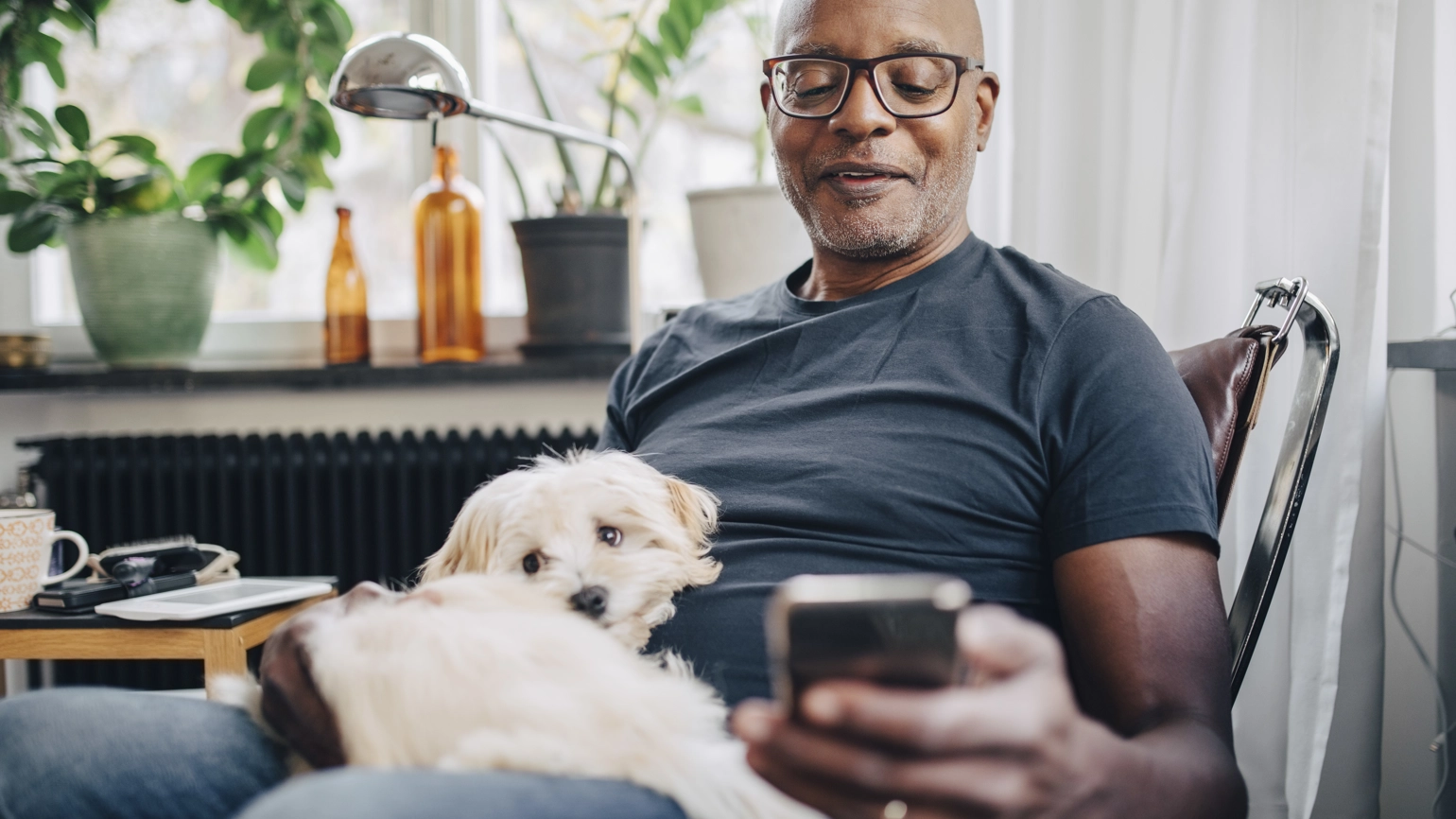 Middle aged male with his dog checking phone in living room Middle aged male with his dog checking phone in living room