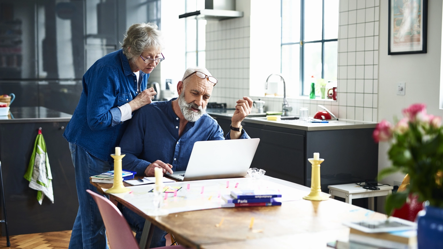 Elderly couple checking laptop in their kitchen dining table Elderly couple checking laptop in their kitchen dining table