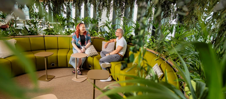 Two employees are talking casually on a curved sofa inside Calon, Legal & General's Welsh HQ