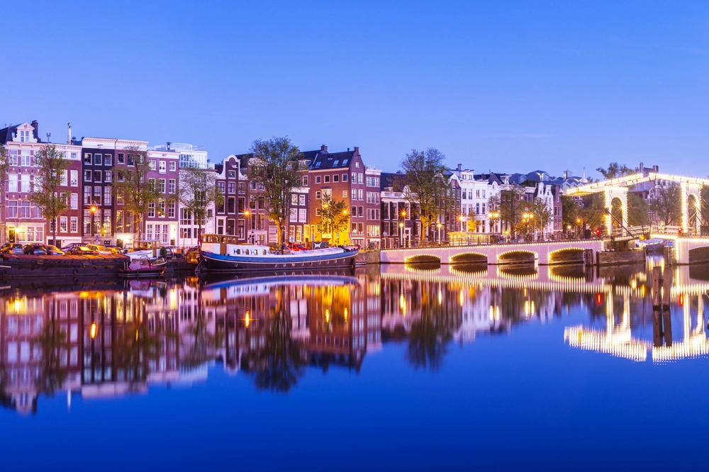 Magere Brug Bridge and canal houses on the Amstel River in Amsterdam, Netherlands, at twilight. Magere Brug Bridge and canal houses on the Amstel River in Amsterdam, Netherlands, at twilight.