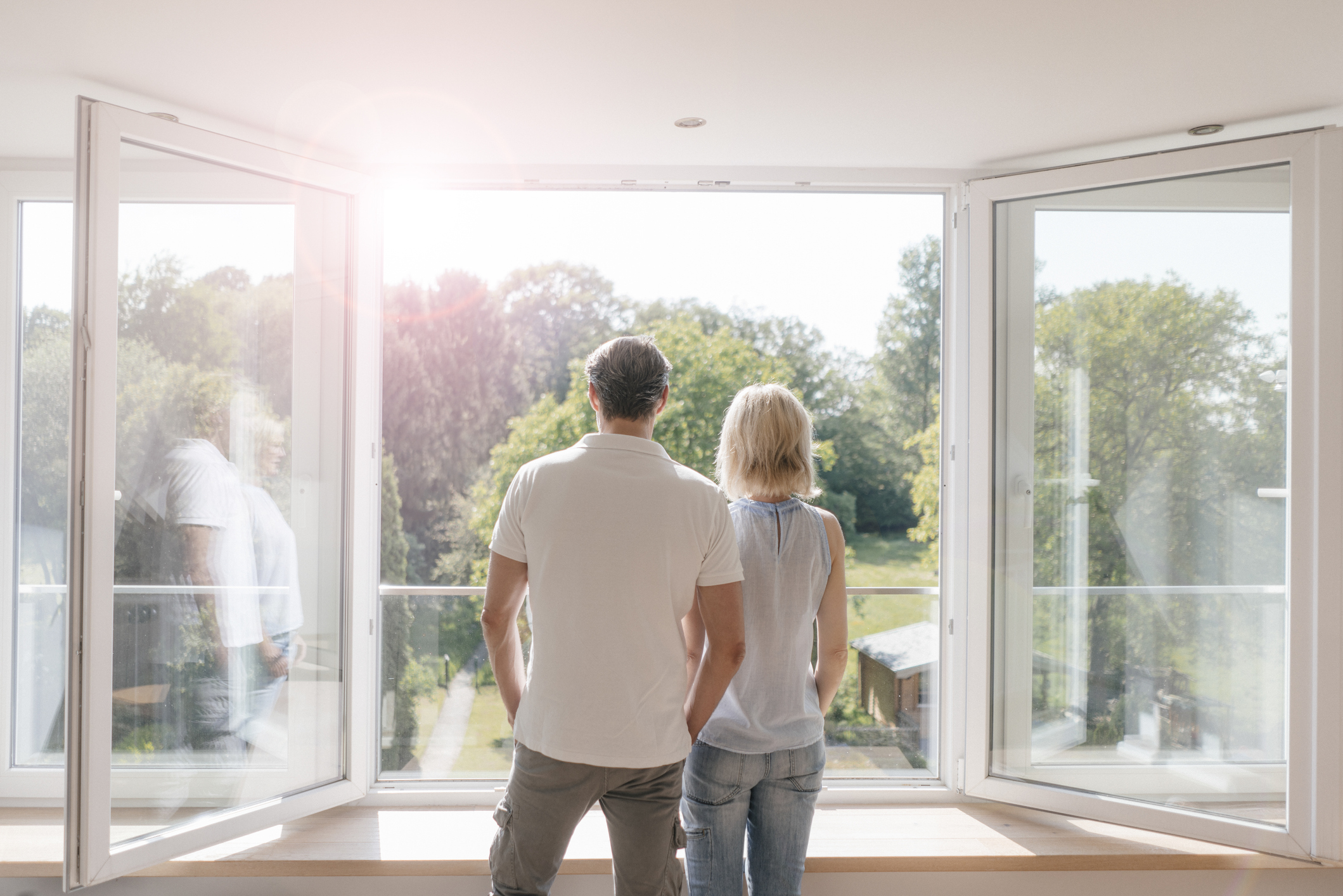 Young couple looking up their back garden through big window