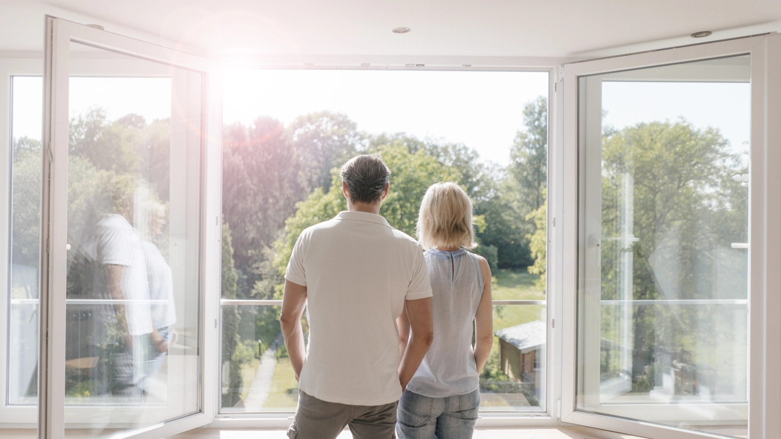 Young couple looking up their back garden through big window Young couple looking up their back garden through big window