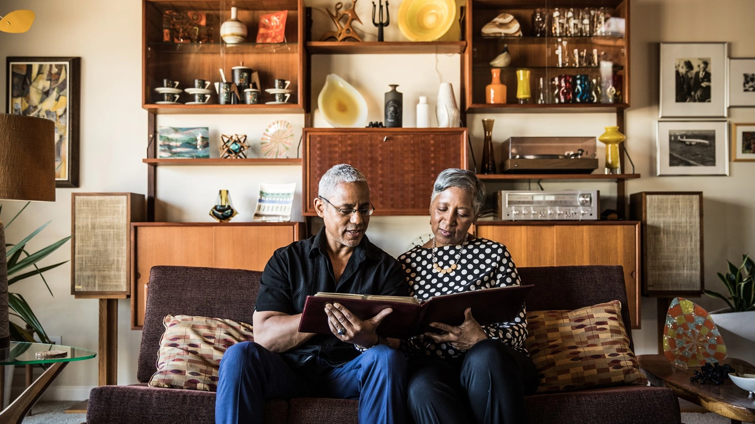 Elderly couple looking photo album in their living room Elderly couple looking photo album in their living room