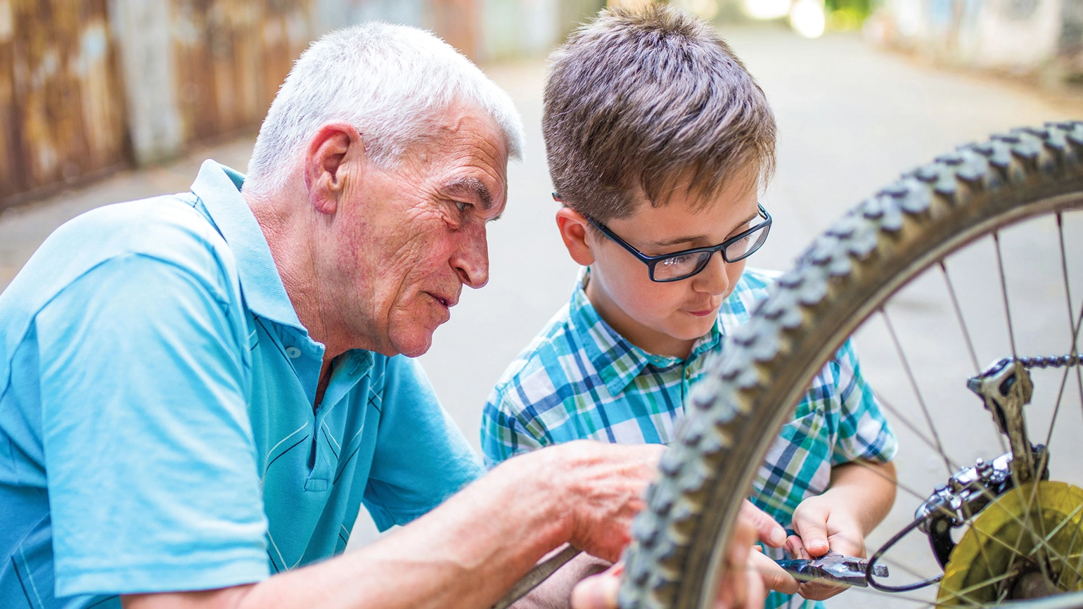 Grandfather and grandson fixing bike together Grandfather and grandson fixing bike together