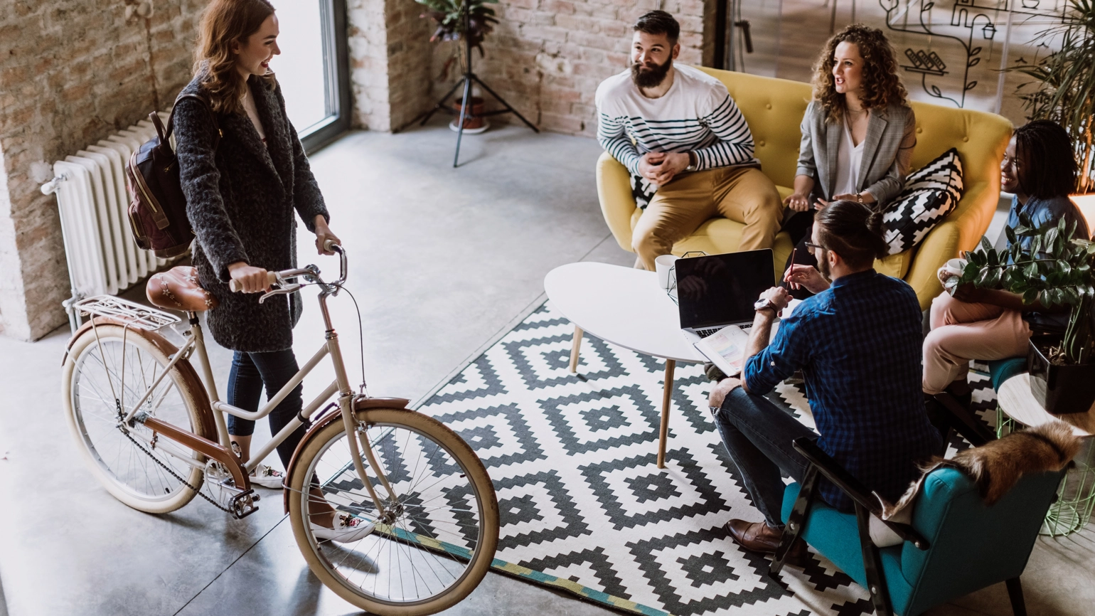 A young woman arrives at a office by bicycle and greets her colleagues. A young woman arrives at a office by bicycle and greets her colleagues.