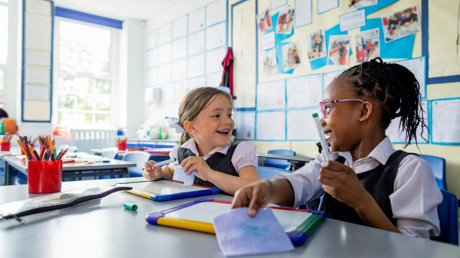 Two female school kids talking in the class room Two female school kids talking in the class room