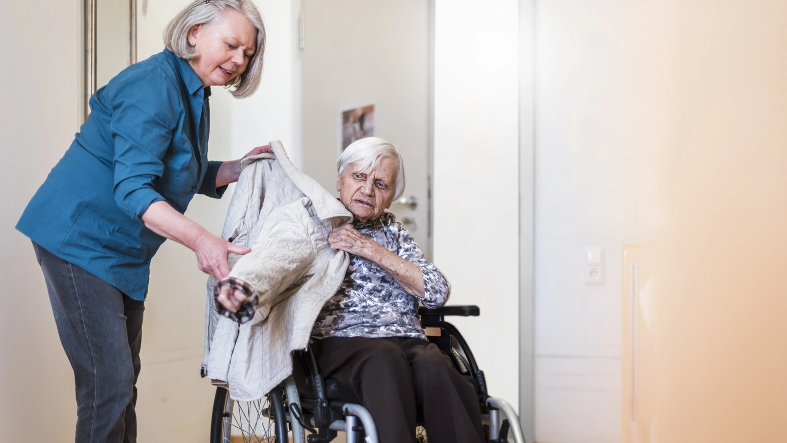 Elderly female helping other elderly female in wheelchair Elderly female helping other elderly female in wheelchair