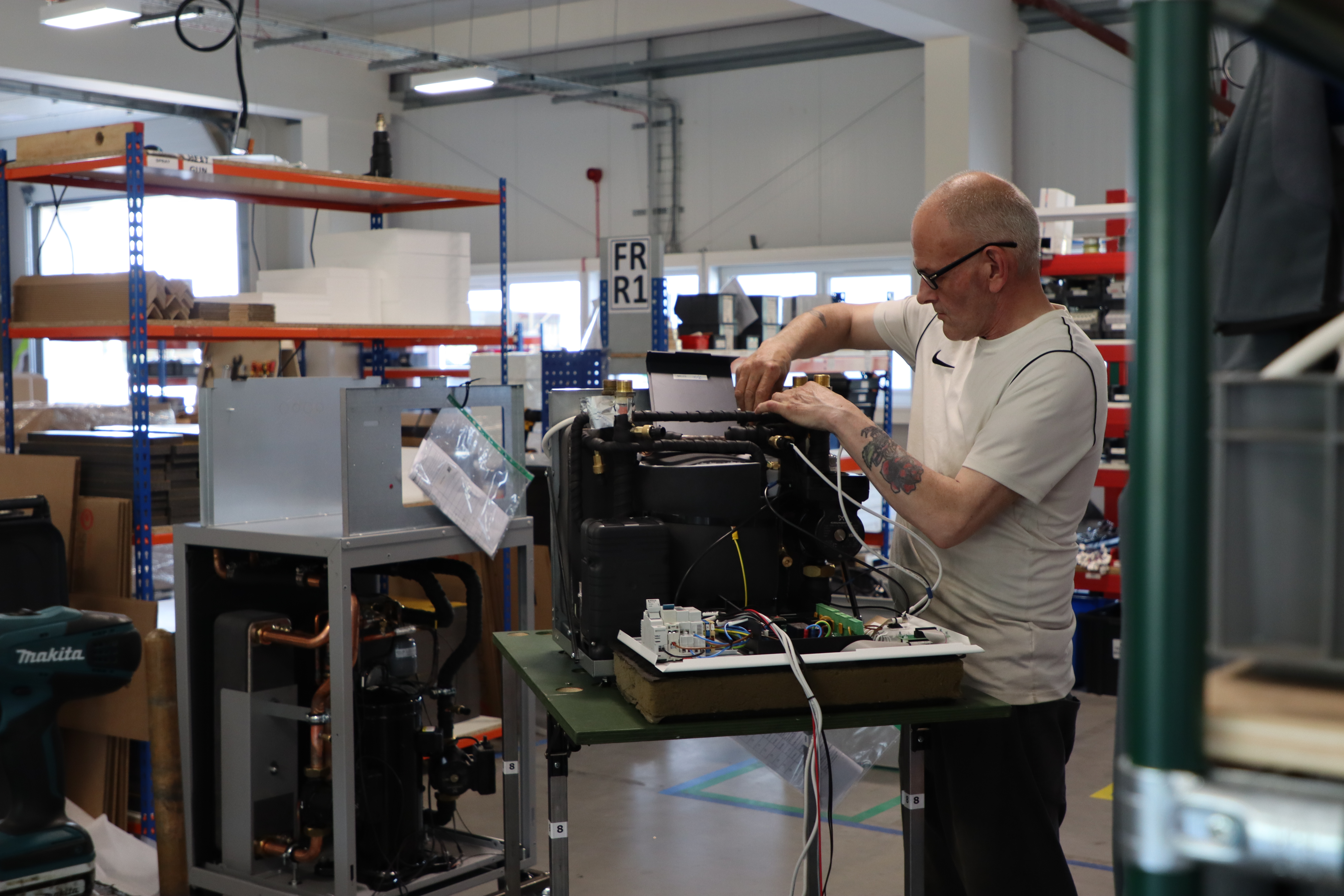 A man works on a machine in the Kensa Heat Pumps factory.
