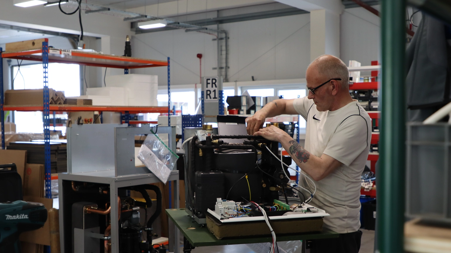 A man works on a machine in the Kensa Heat Pumps factory. A man works on a machine in the Kensa Heat Pumps factory.