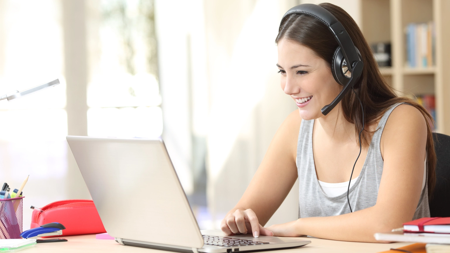 Female worker working with her laptop with headset on Female worker working with her laptop with headset on