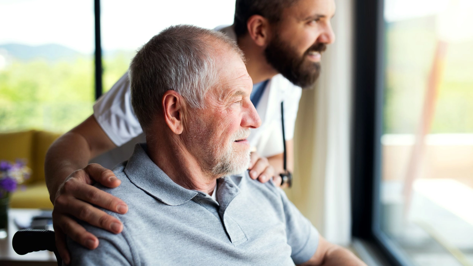 Elderly patient and a doctor watching the view through window Elderly patient and a doctor watching the view through window