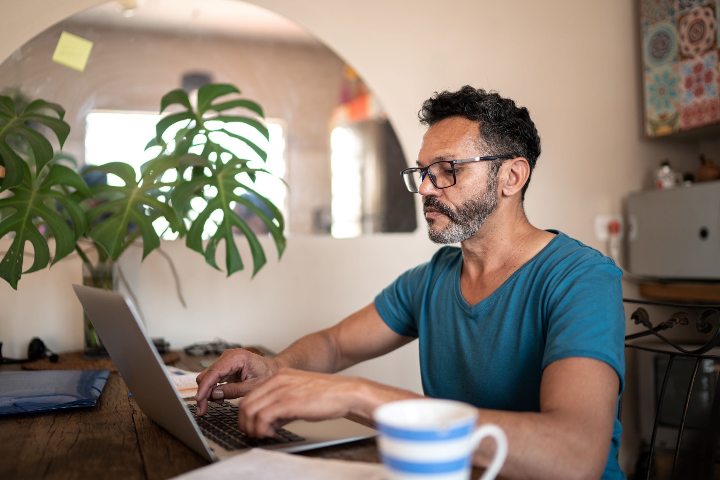 Middle aged male checking his laptop in their dining table 