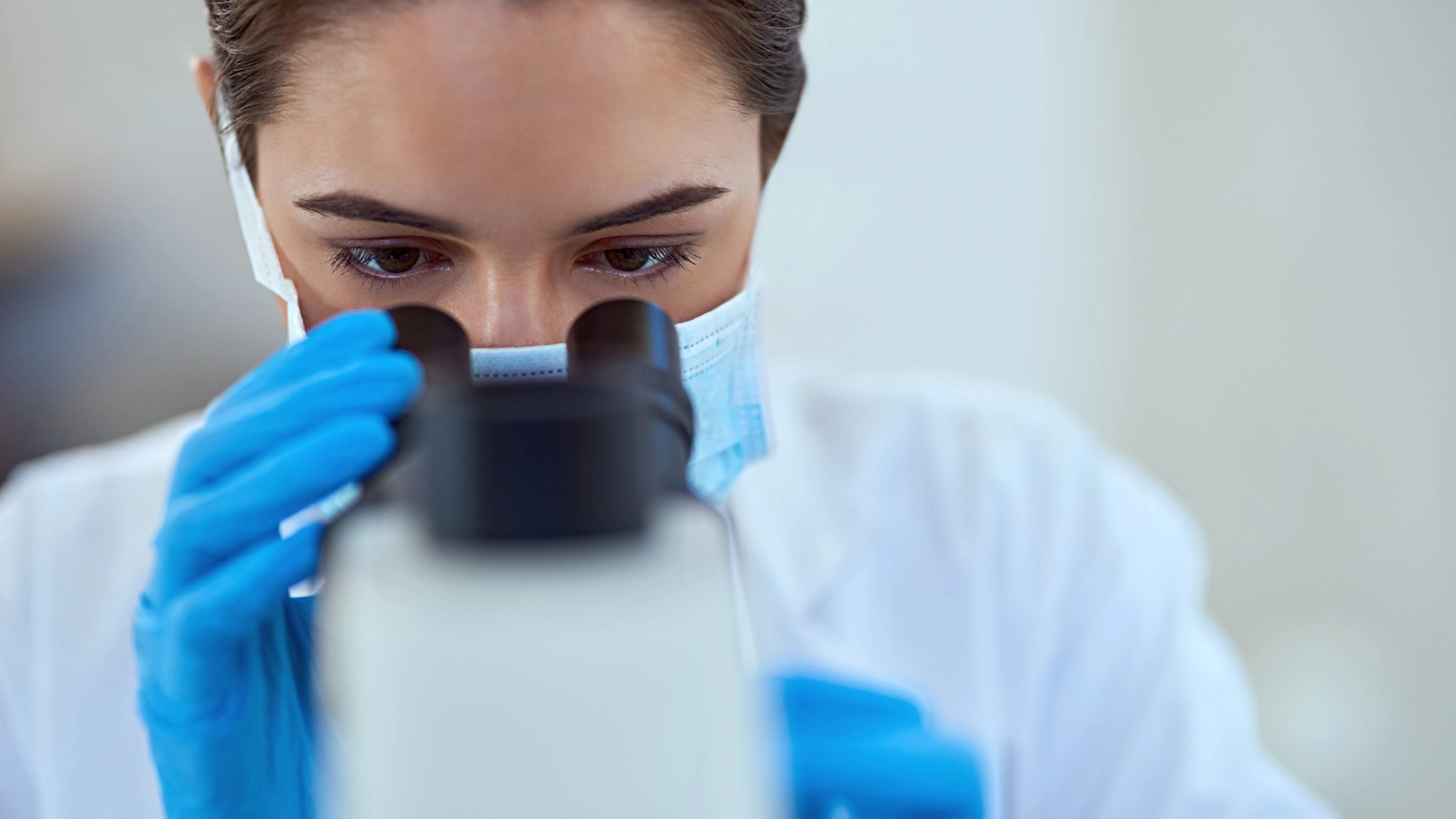 Female researcher checking microscope Female researcher checking microscope
