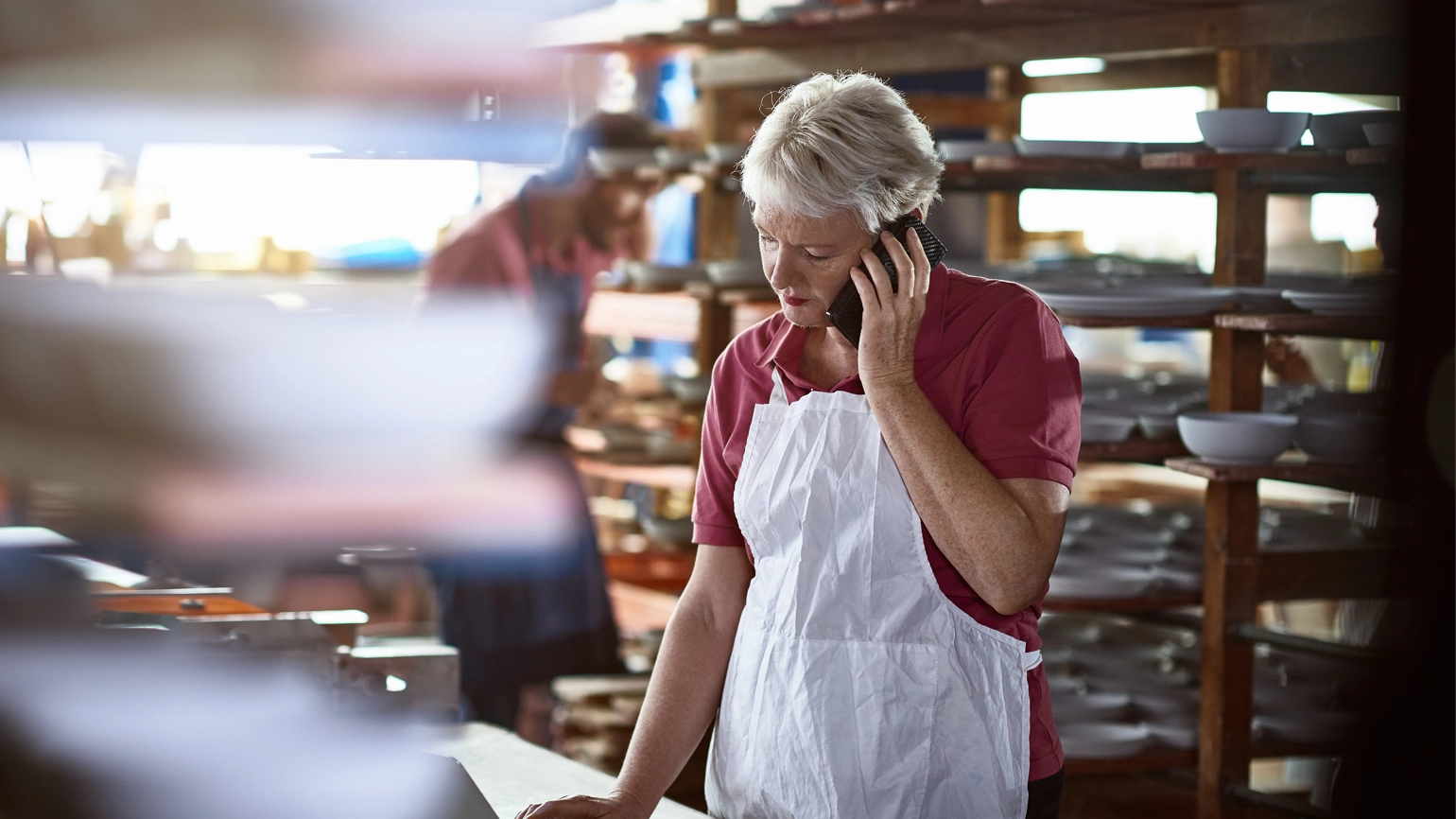 Female business owner receiving a call while checking her laptop at her work Female business owner receiving a call while checking her laptop at her work