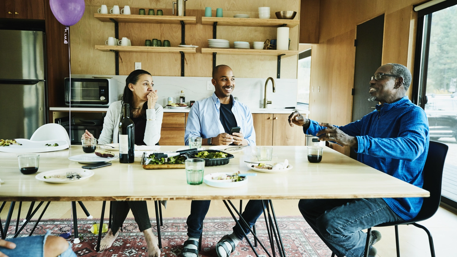 One elderly male, one young male, and one young female chatting in the kitchen dining table One elderly male, one young male, and one young female chatting in the kitchen dining table