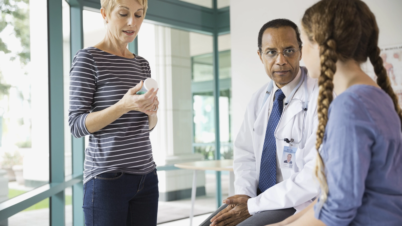 Doctor checking young female patient and patient's mom checking medication Doctor checking young female patient and patient's mom checking medication