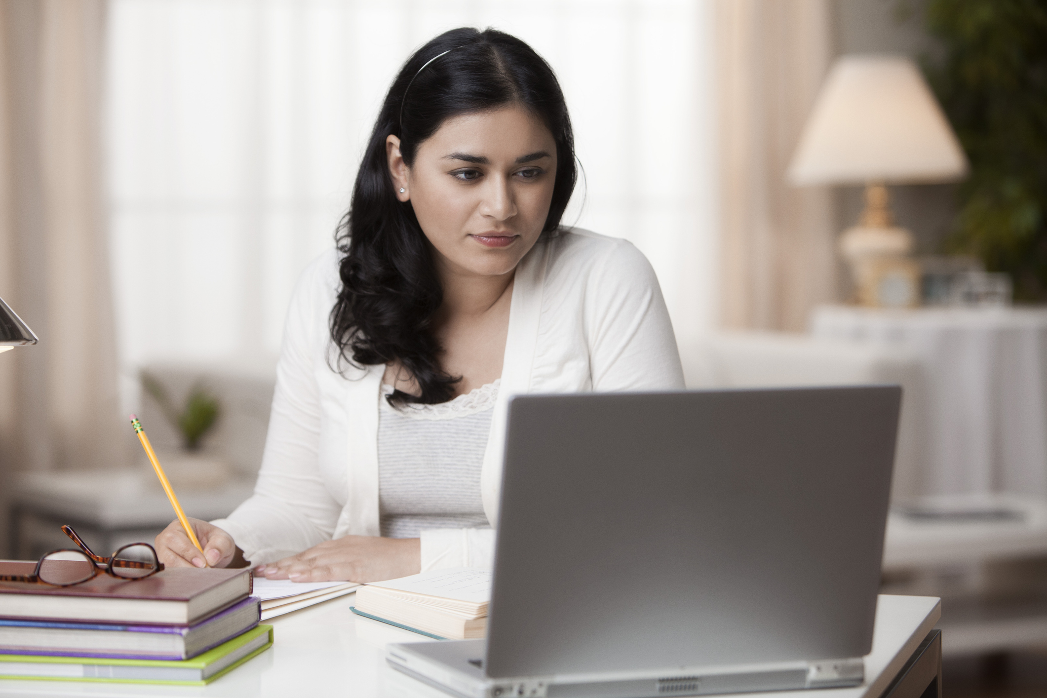 Female checking laptop while taking notes 