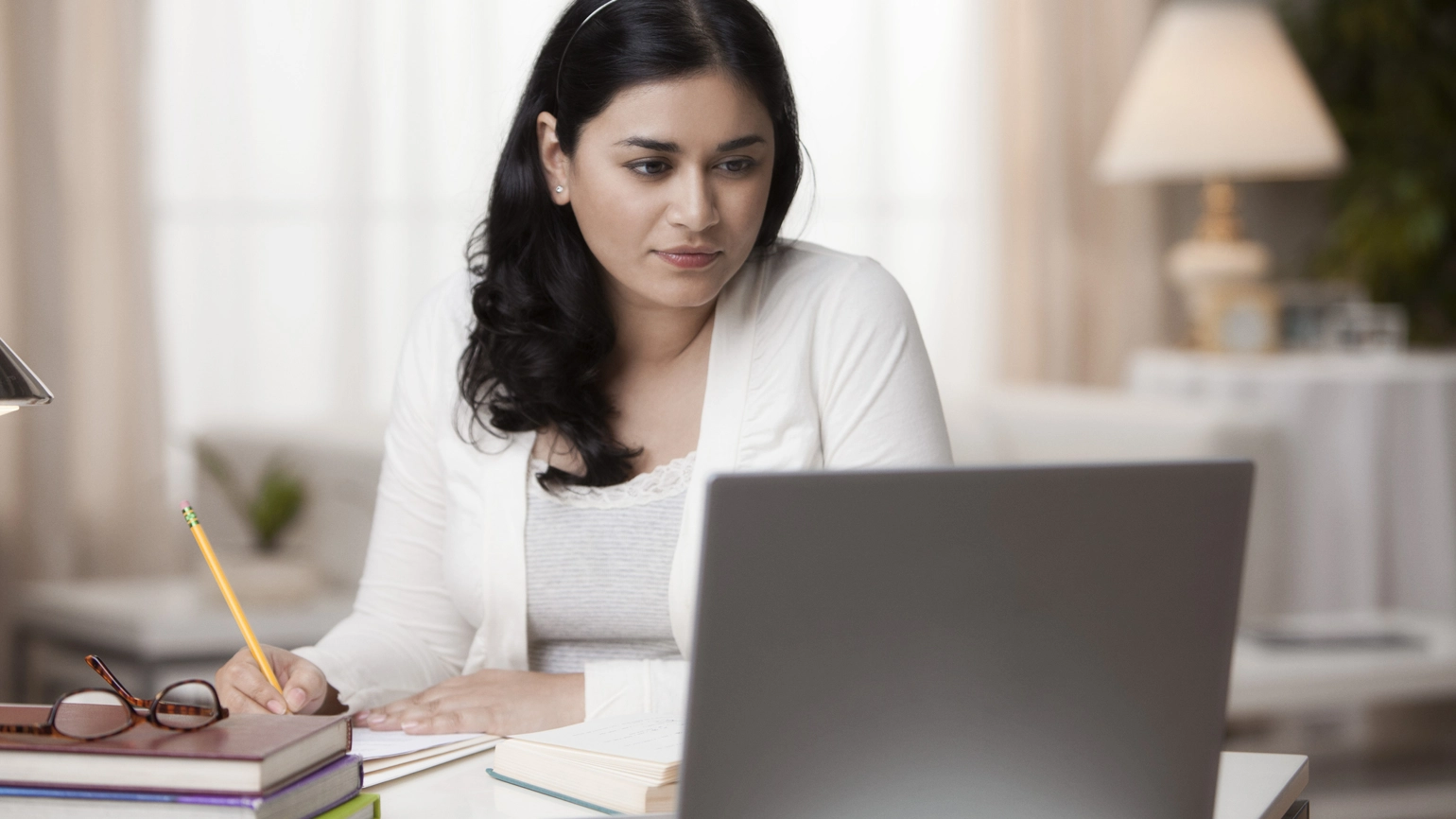Female checking laptop while taking notes Female checking laptop while taking notes