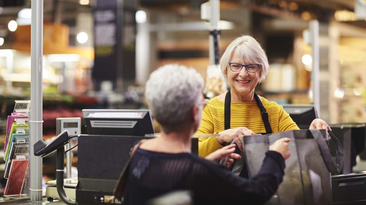 elderly cashier and elderly customer in the supermarket elderly cashier and elderly customer in the supermarket