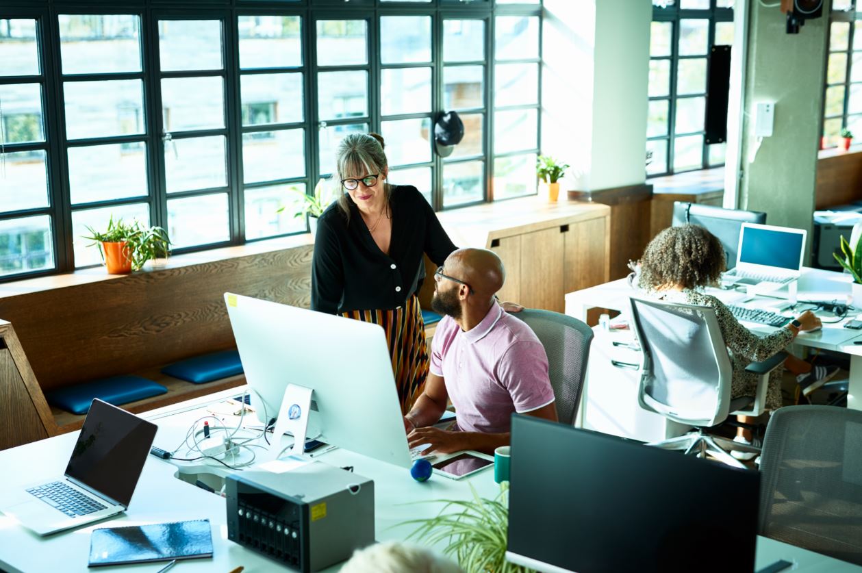 Female colleague helping male colleague out in the office 