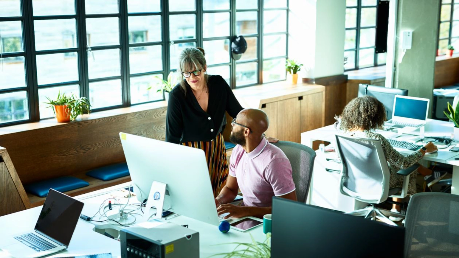 Female colleague helping male colleague out in the office  Female colleague helping male colleague out in the office