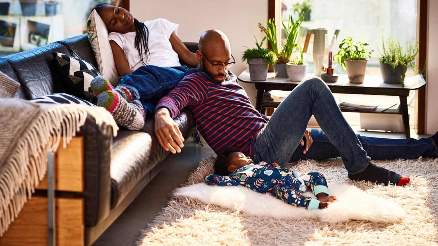 Young family in the living room mother sitting on sofa, father sitting on the floor looking at their son Young family in the living room mother sitting on sofa, father sitting on the floor looking at their son