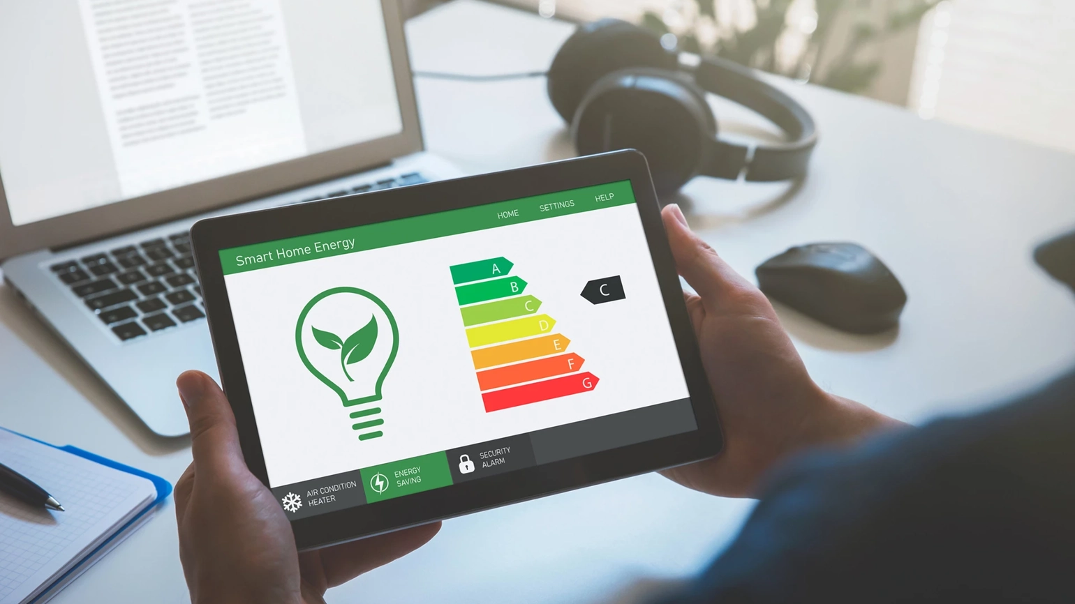 Photograph of a person's hands holding an iPad with energy rating on the screen Photograph of a person's hands holding an iPad with energy rating on the screen