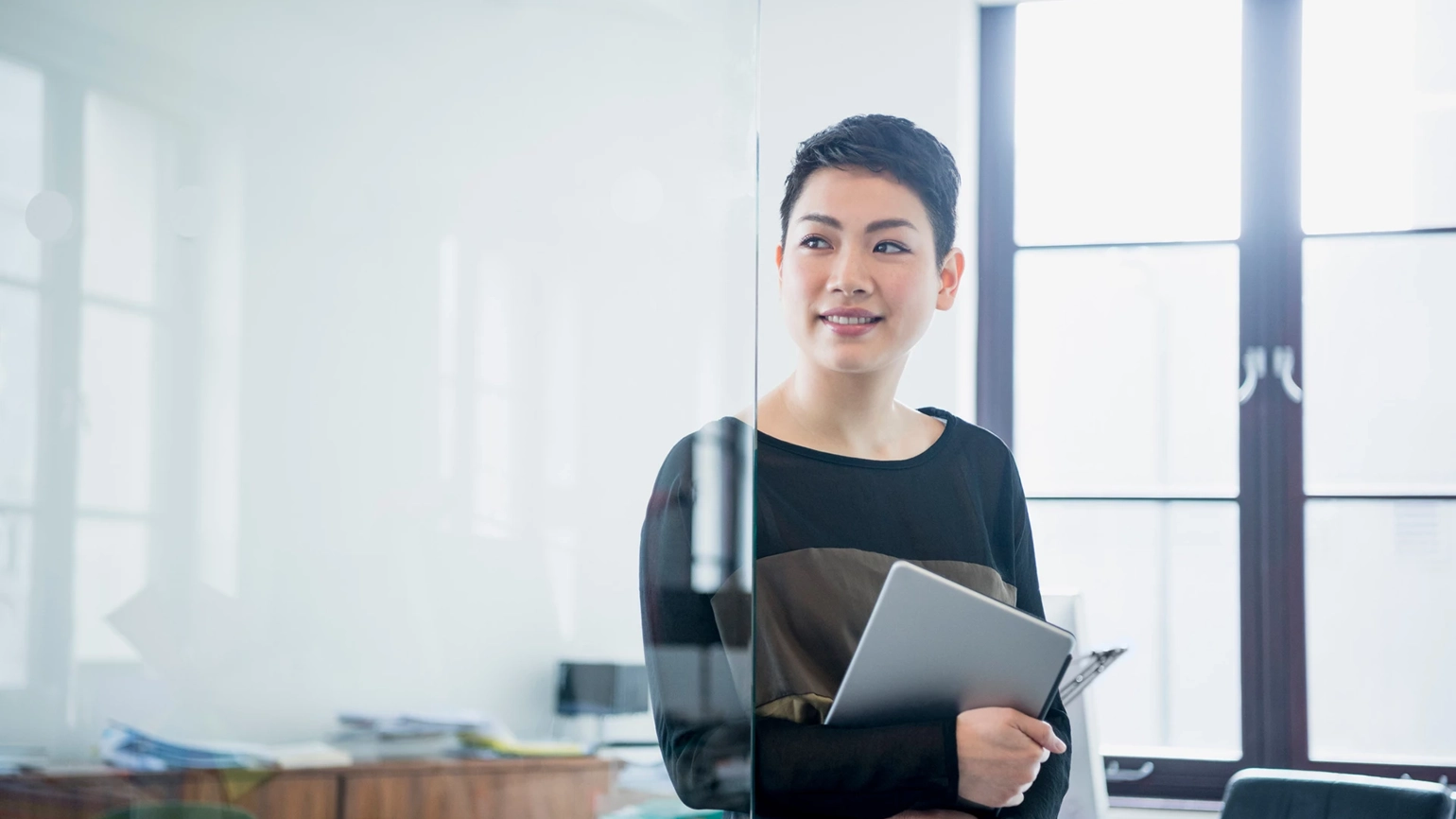 Photograph of a woman in an office holding an iPad Photograph of a woman in an office holding an iPad