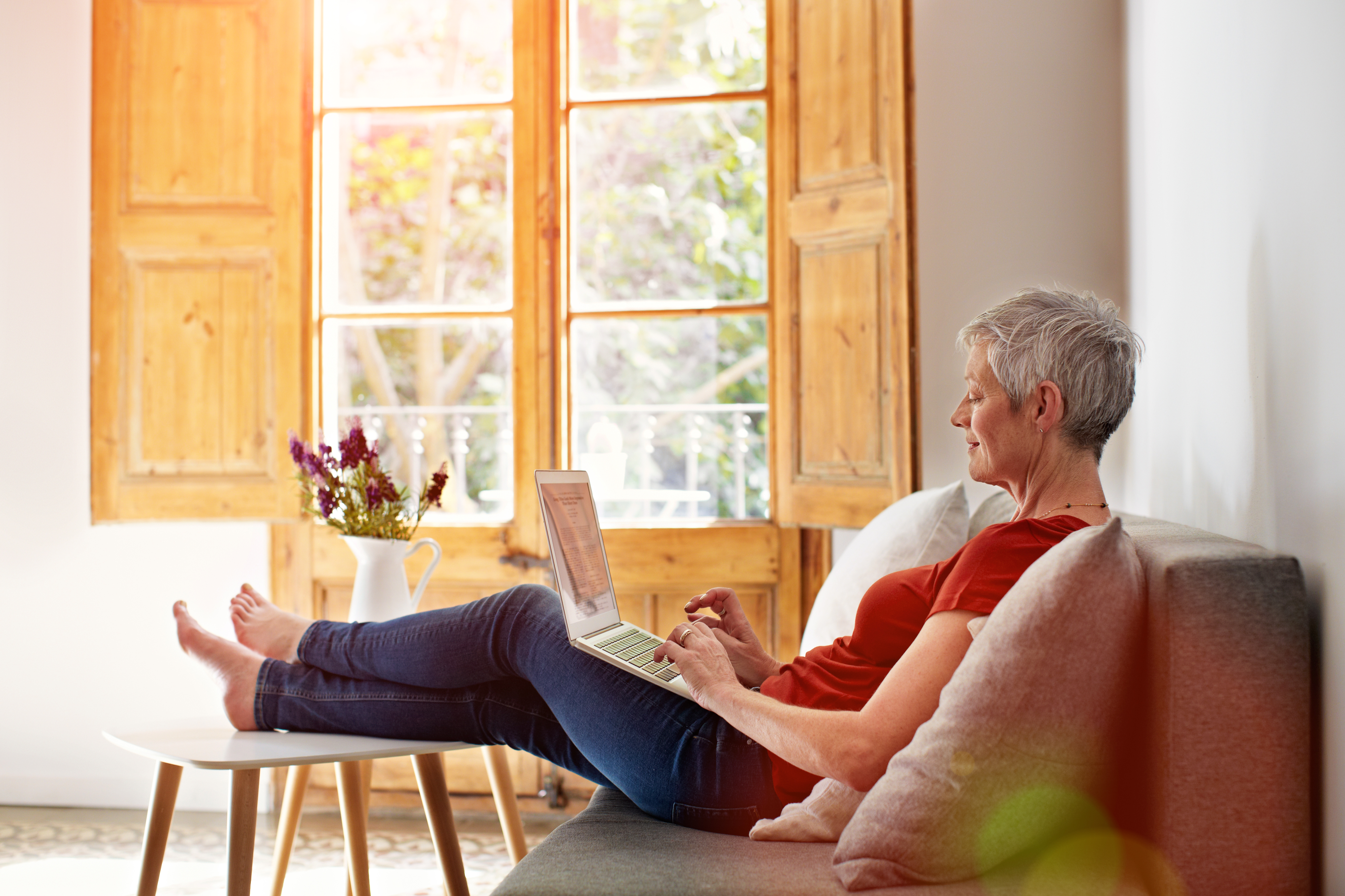 Elderly female checking laptop in her living room 
