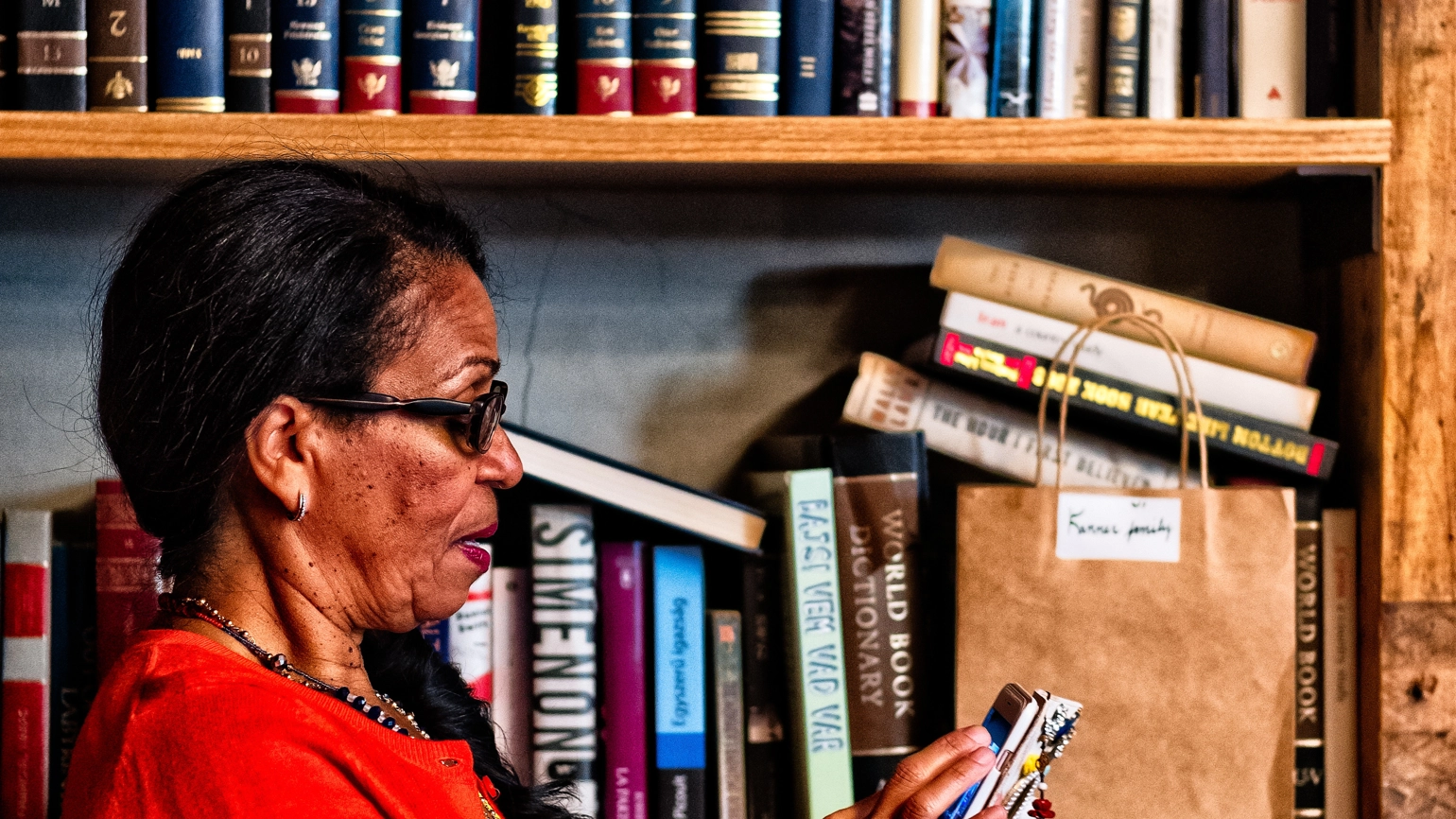 Elderly female checking her phone in her library Elderly female checking her phone in her library