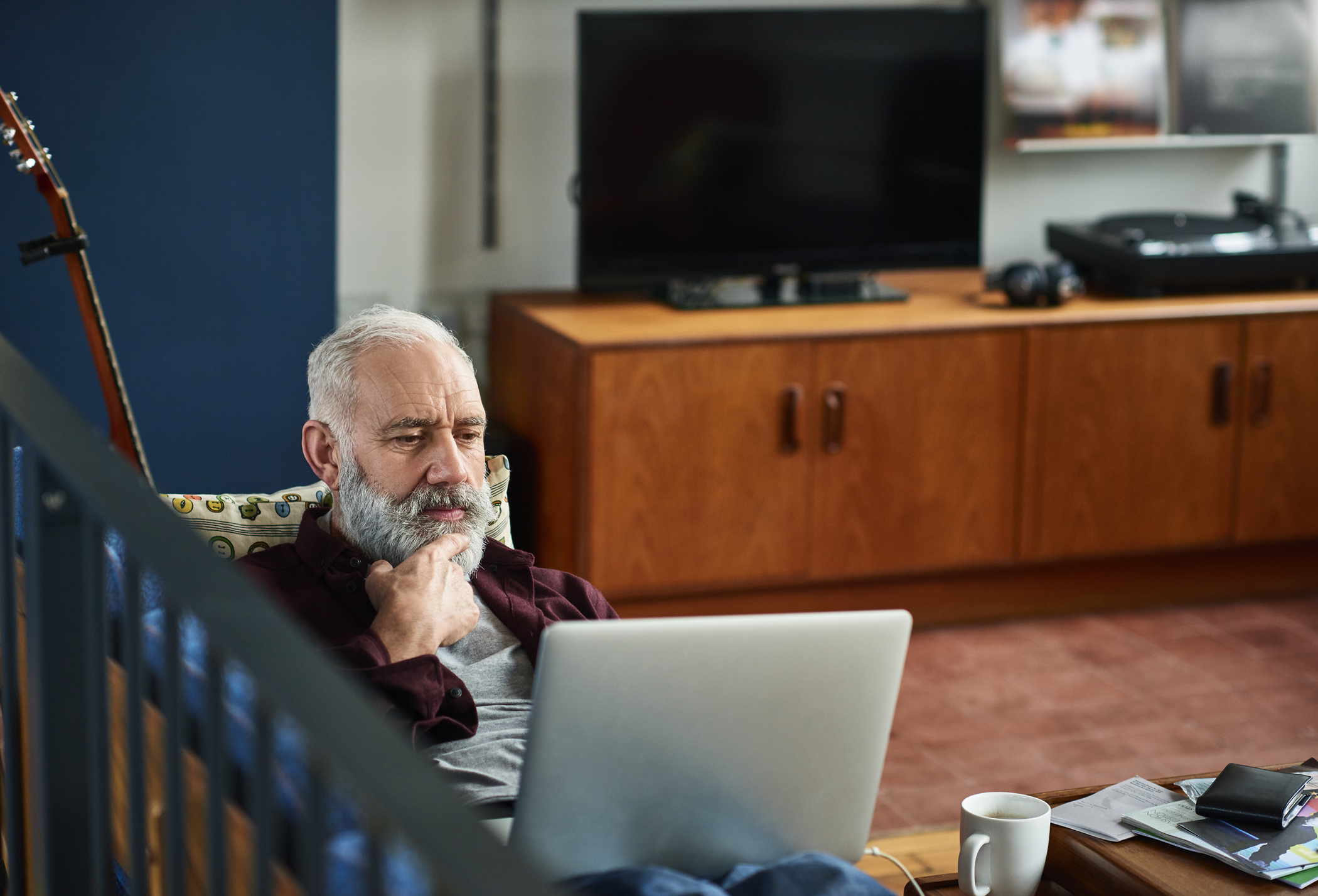 Elderly male checking his laptop in his living room 