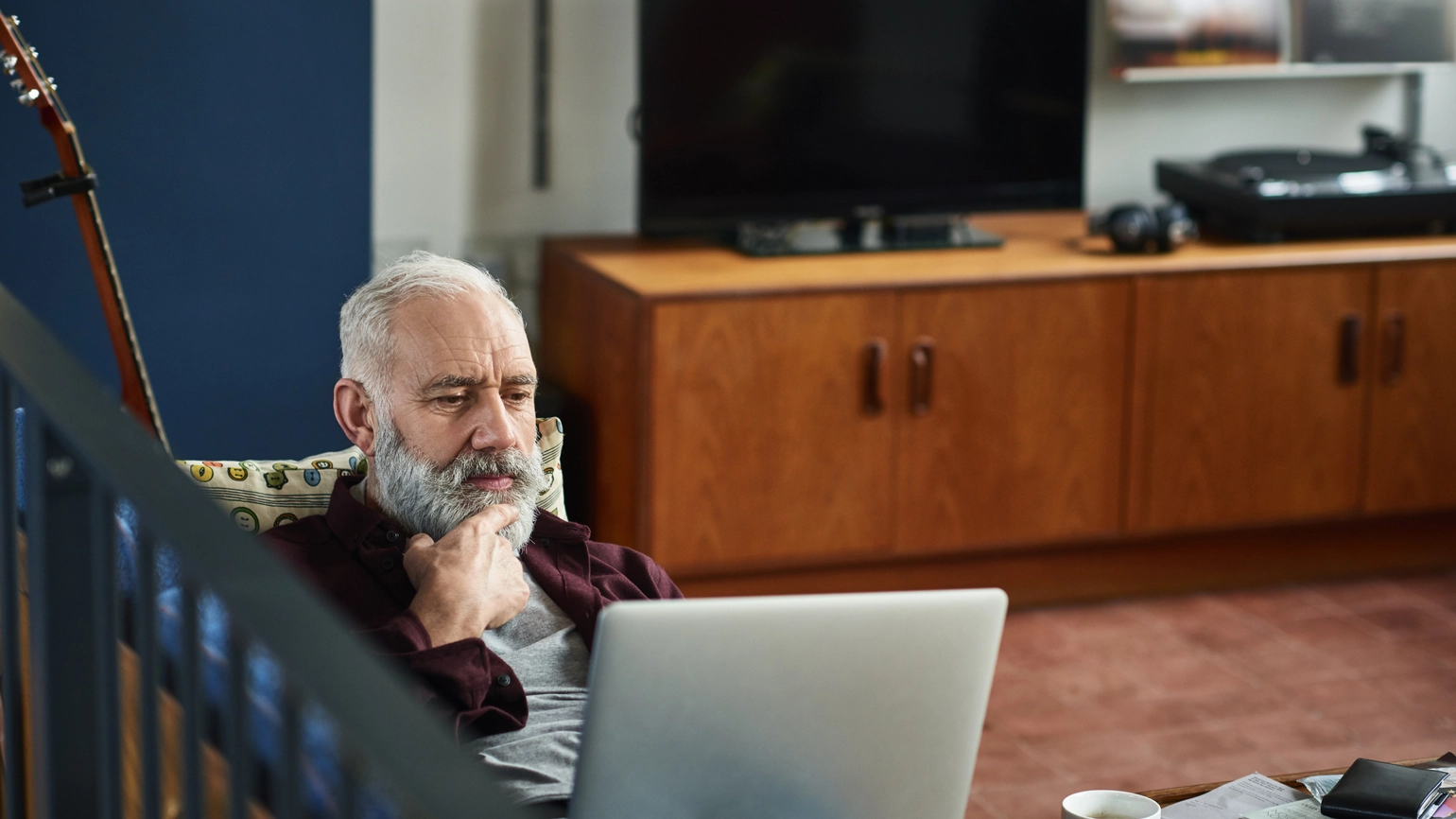Elderly male checking his laptop in his living room  Elderly male checking his laptop in his living room