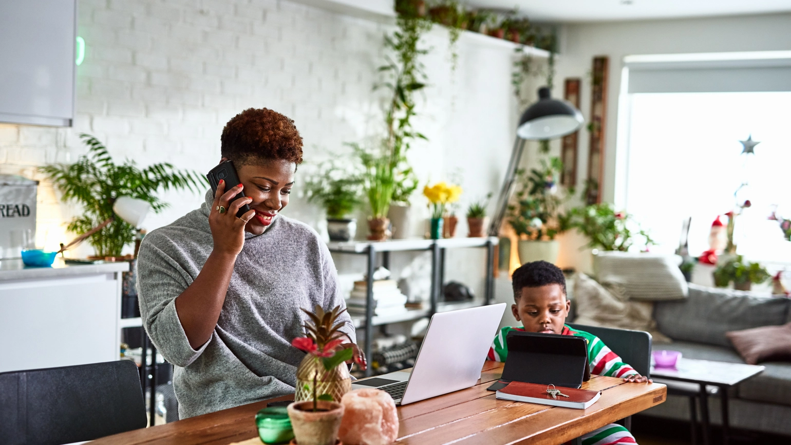 Father having a call with his laptop on and his son checking touch pad in the dining table Father having a call with his laptop on and his son checking touch pad in the dining table