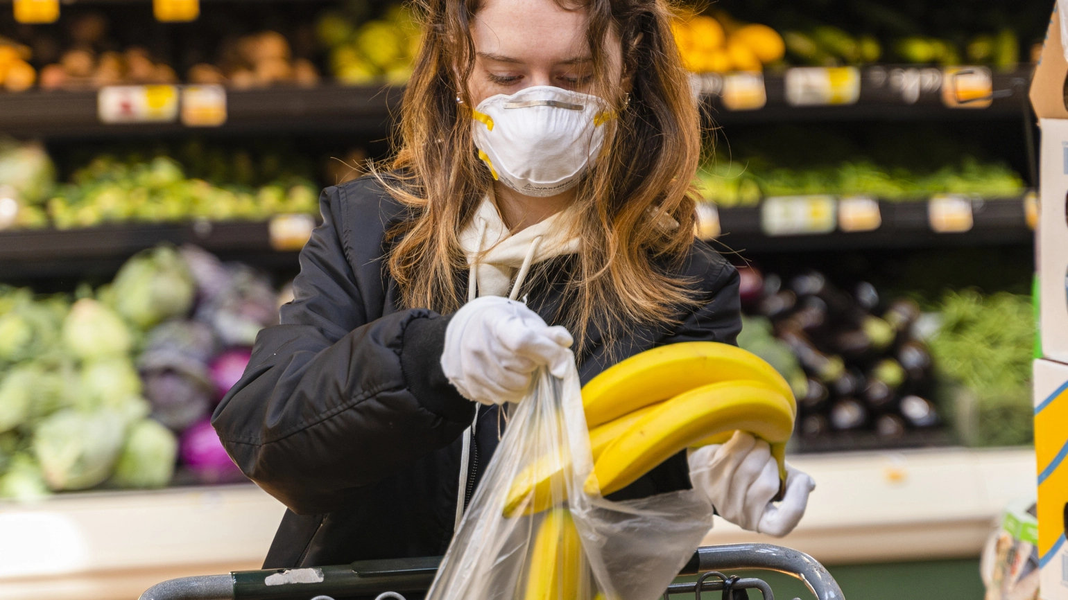 Female picking banana from supermarket with face masks on Female picking banana from supermarket with face masks on
