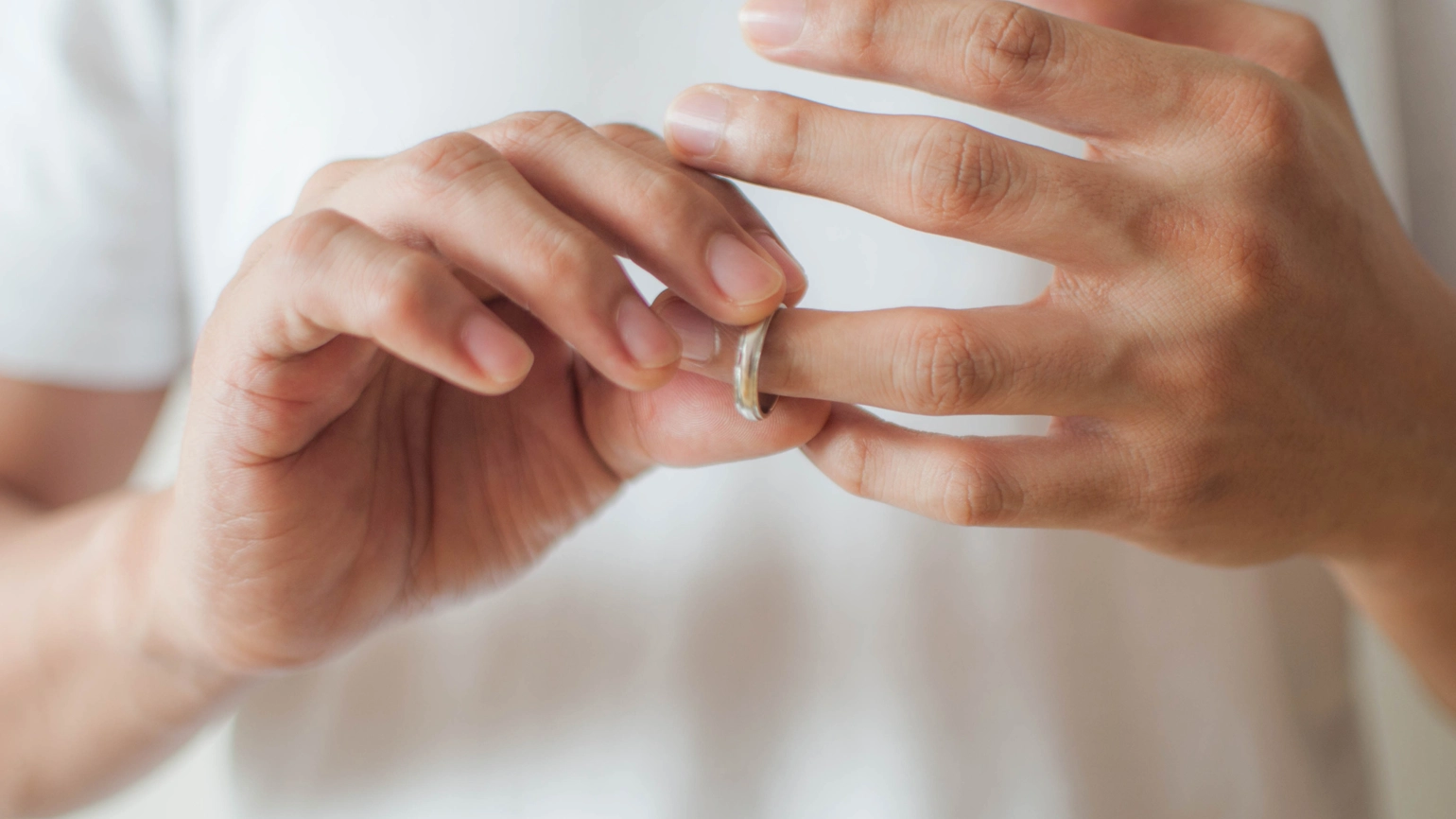 Male taking wedding ring off from his hand Male taking wedding ring off from his hand