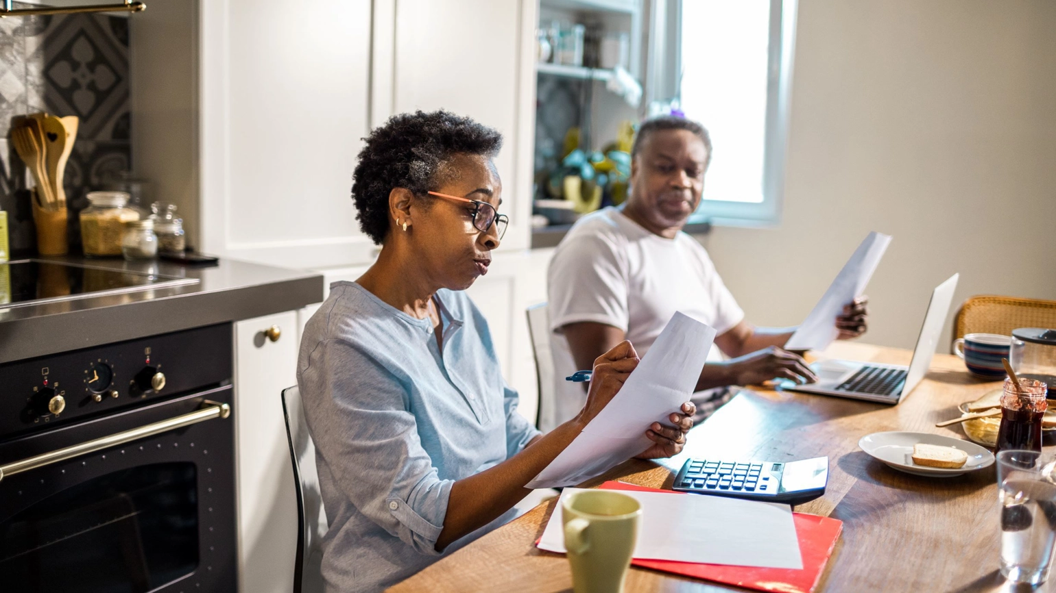 Middle aged couple going through their documents and laptop in the dining table Middle aged couple going through their documents and laptop in the dining table