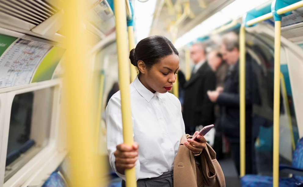 Businesswoman in underground train looking at cell phone