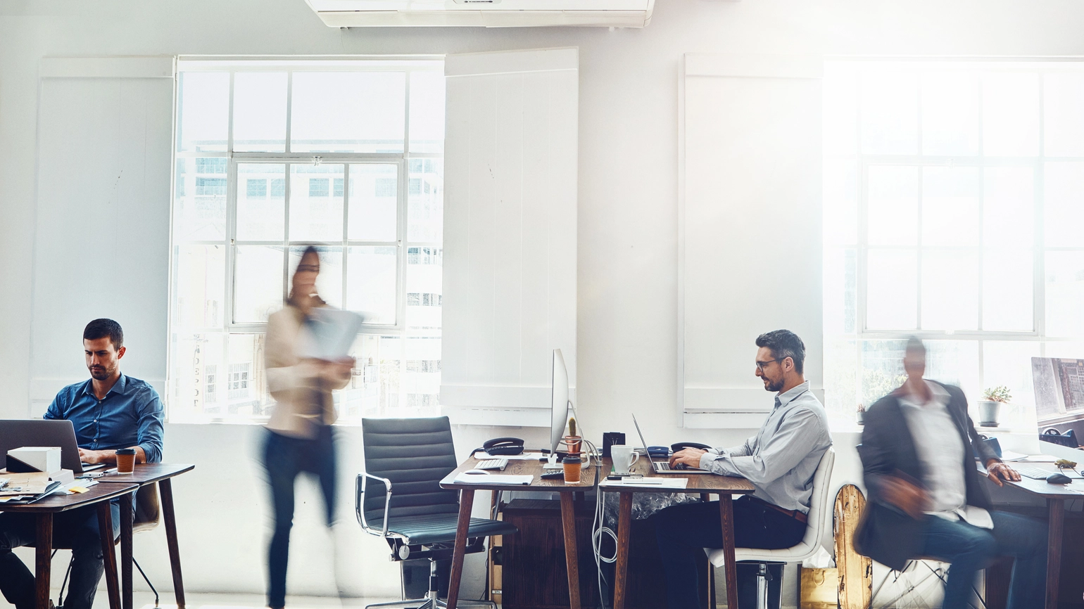 Photo of busy working space with 4 office workers working Photo of busy working space with 4 office workers working