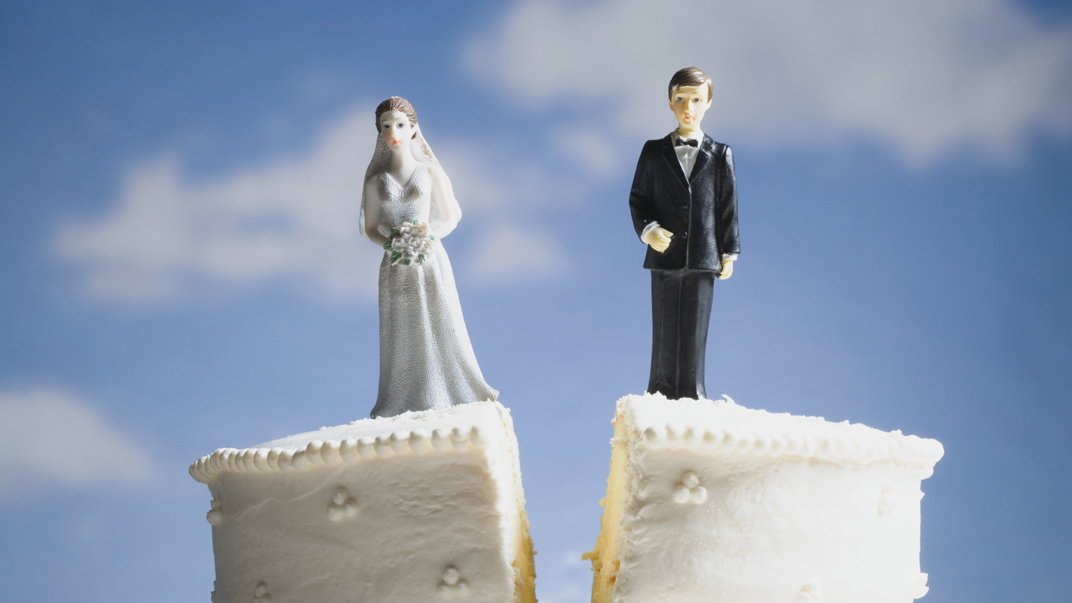Bride and groom figurines standing on two separated slices of wedding cake. Bride and groom figurines standing on two separated slices of wedding cake.