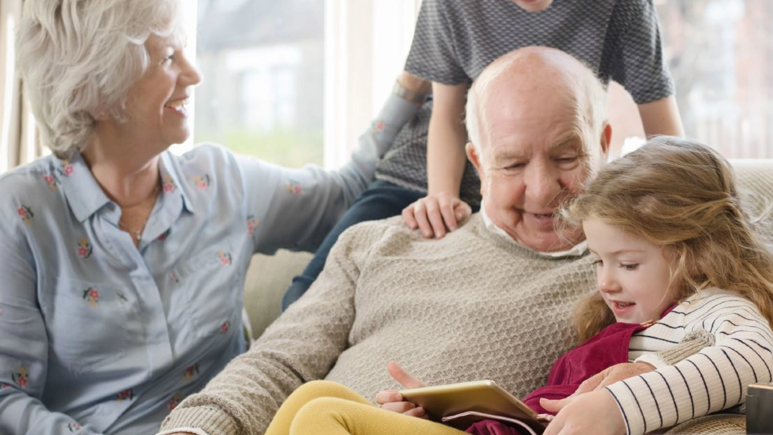 Grandparents and grandkids checking touch screen together in their living room Grandparents and grandkids checking touch screen together in their living room