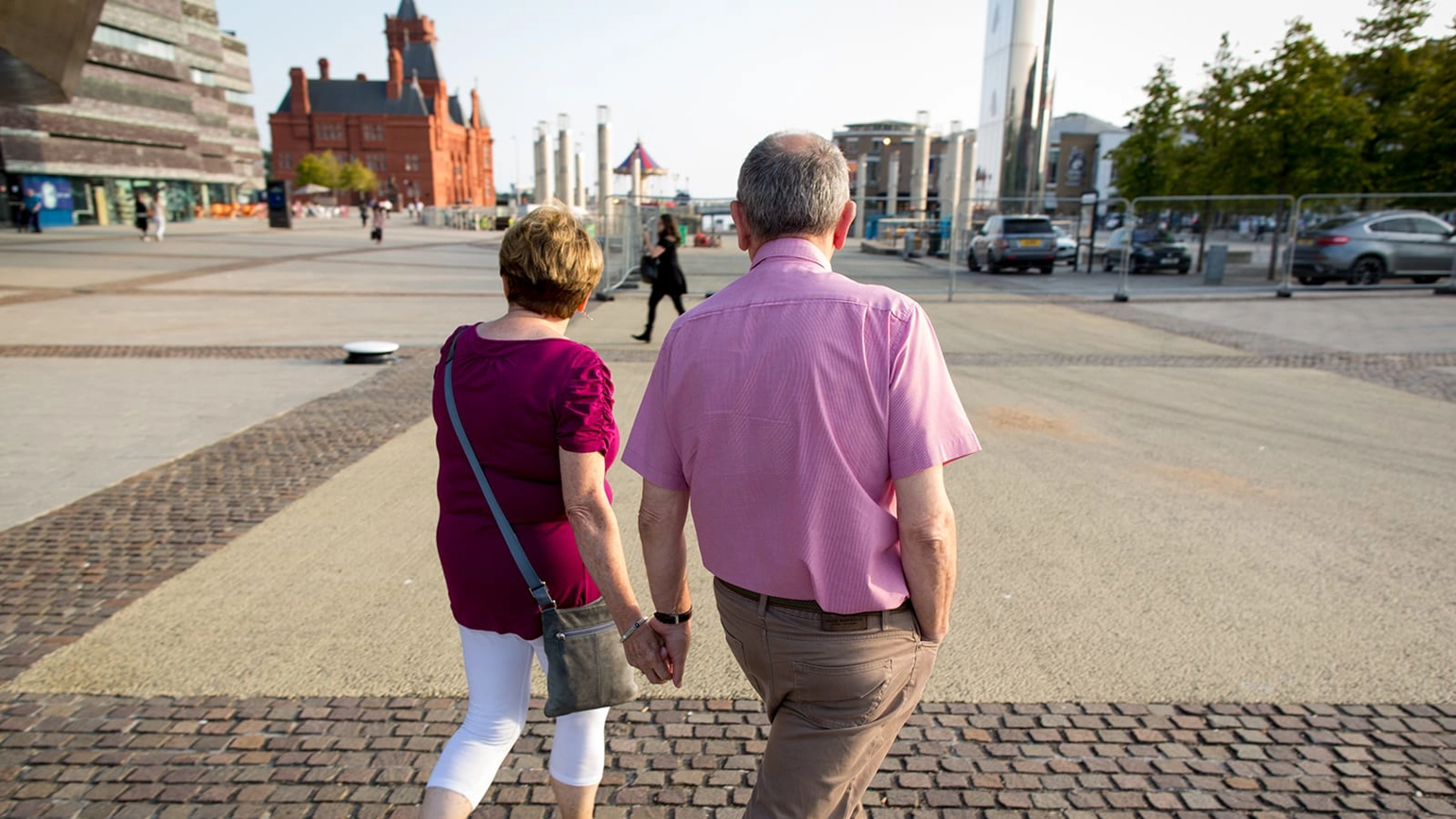Elderly couple walking in the streets holding hands together Elderly couple walking in the streets holding hands together