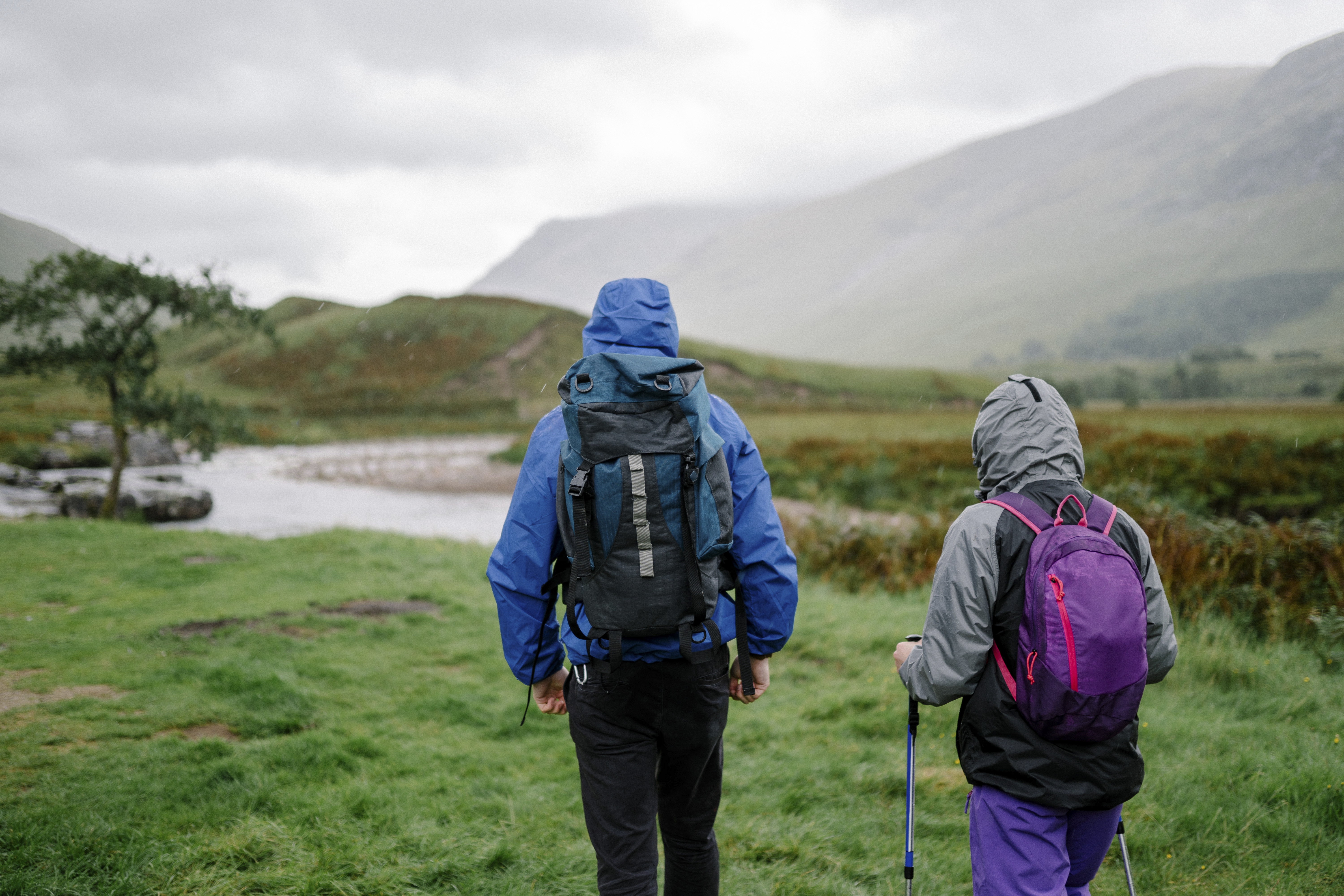 A couple trekking through the rain in the Scottish Highlands.